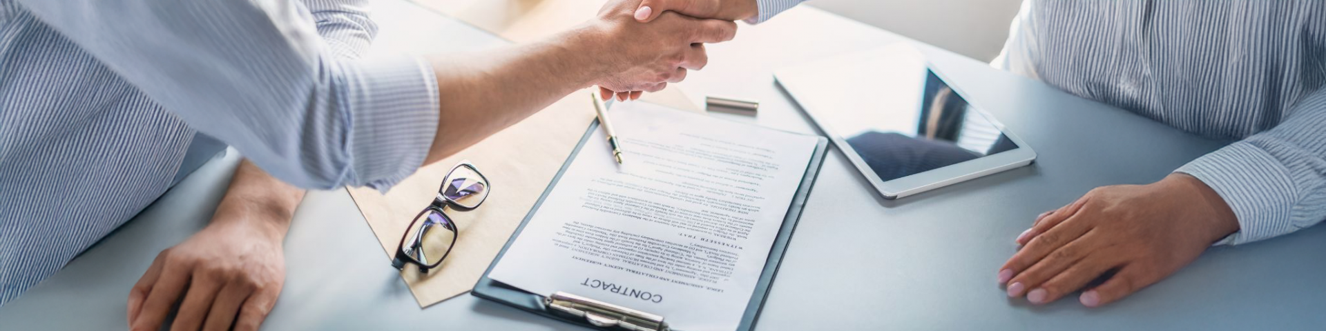 Dos personas se dan la mano de común acuerdo al firmar un contrato